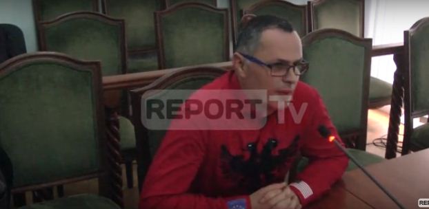 VIDEO/ Oficeri i policisë Xhelili bën “show” në dëshminë për IMSI Catcher, i veshur kuq e zi, me flamurin amerikan dhe europian dhe këndon himnin