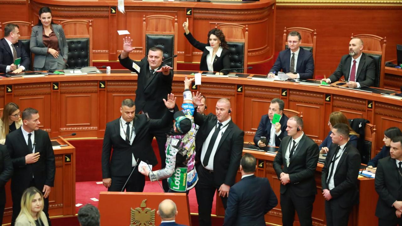 FOTOGALERI/ Deputeti Dashnor Sula  veshur me logo llotosh dhe dollarë, hedh tufa dollaresh mbi deputetët dhe ministrat socialistë